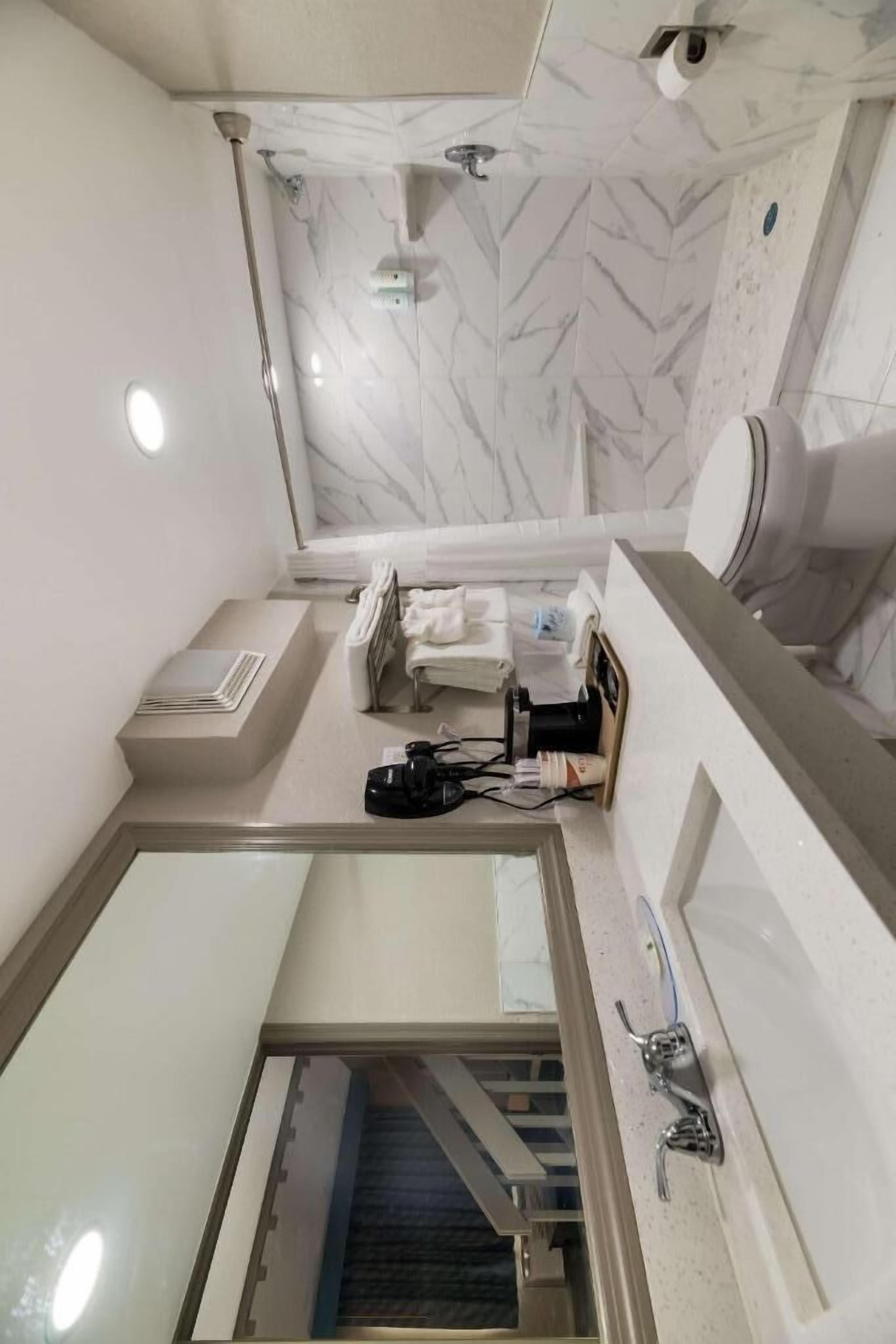 Un baño con detalles de mármol en el respuesto, zona de ducha y tocador con espejo.