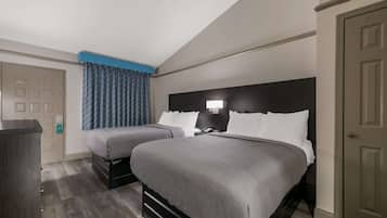 Ein Hotelzimmer mit zwei Betten, einem Schreibtisch und einer Tür.