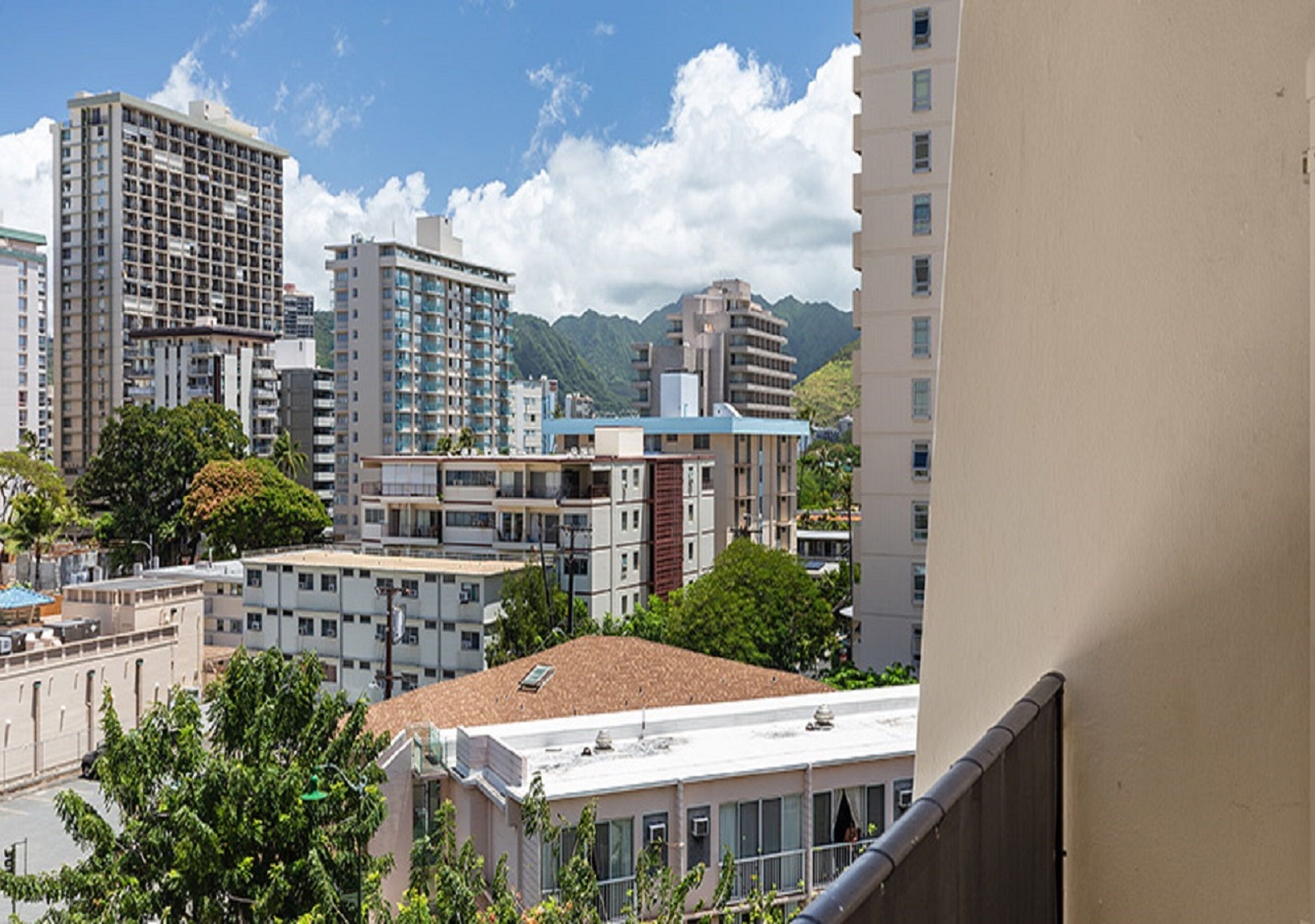 A cityscape with multiple high-rise buildings, a mix of residential and commercial structures, and a mountainous backdrop.