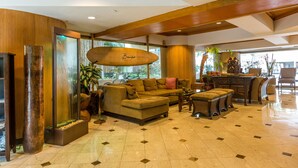 A spacious lobby with a large sofa, a coffee table, and a dining area. - Castle Bamboo Waikīkī Hotel (Honolulu)
