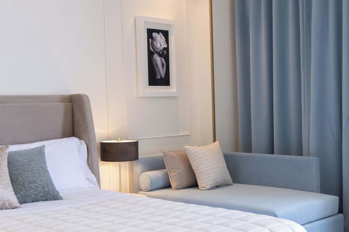 Una habitación de hotel con cama, sofá, un cuadro en la pared y una lámpara.