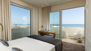 A hotel room with a large bed, a desk with a chair, and a view of the beach and ocean.