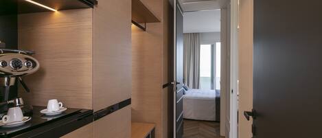 Habitación de hotel moderna con kitchenette, una cama y un baño visible a través de una puerta abierta.