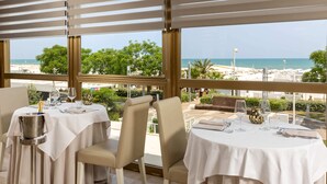 A restaurant with tables set for dining, featuring a view of the beach and ocean.