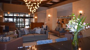A modern lobby with a central seating area, a large chandelier, and a vase of flowers.