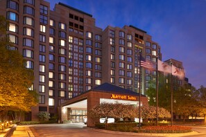 Een Marriott Suites hotel met een groot gebouw, een goed verlichte ingang en een vlag.