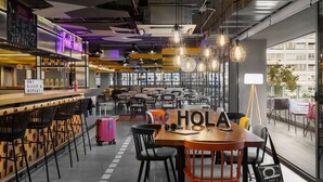Un café moderno con barra, asientos y un letrero que dice 'HOLA'.