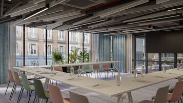 A modern conference room with a long table, multiple chairs, and a large screen.