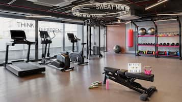 Un gimnasio con cintas de correr, elípticas y equipo de levantamiento de pesas.
