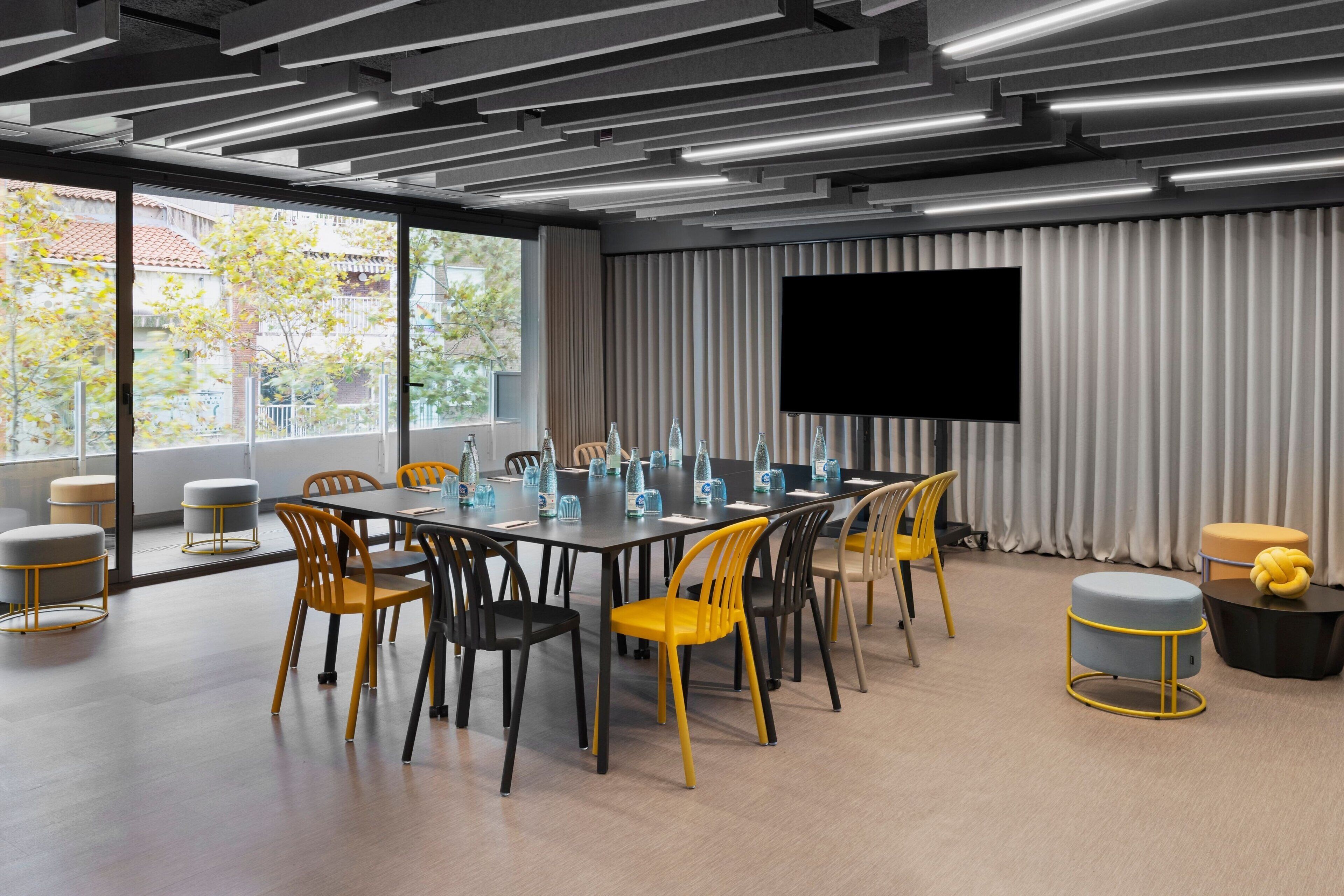A modern conference room with a large table, chairs, and a flat-screen TV.