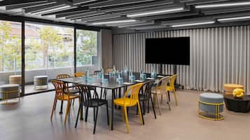 Une salle de conférence moderne équipée d’une grande table, de chaises et d’un téléviseur à écran plat.