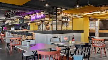 Un restaurante moderno con zona de bar, diferentes disposiciones de asientos y un letrero de neón.