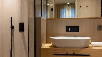A modern bathroom with a glass-enclosed shower, a large mirror, and a wooden vanity with a white sink.