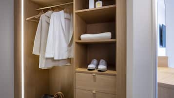 A wooden wardrobe with hanging clothes, a shelf with shoes, and a drawer.