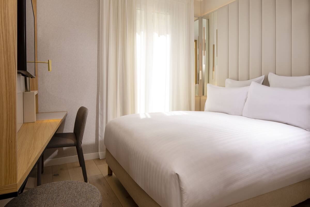 Une chambre d’hôtel avec un lit, un bureau et une chaise.