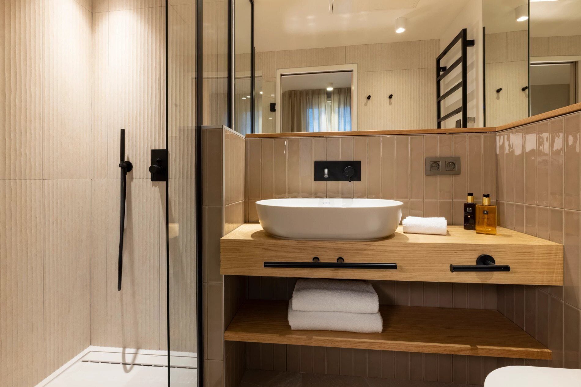 Une salle de bain moderne avec un grand lavabo sur pied, un meuble-lavabo en bois et une douche à paroi de verre.