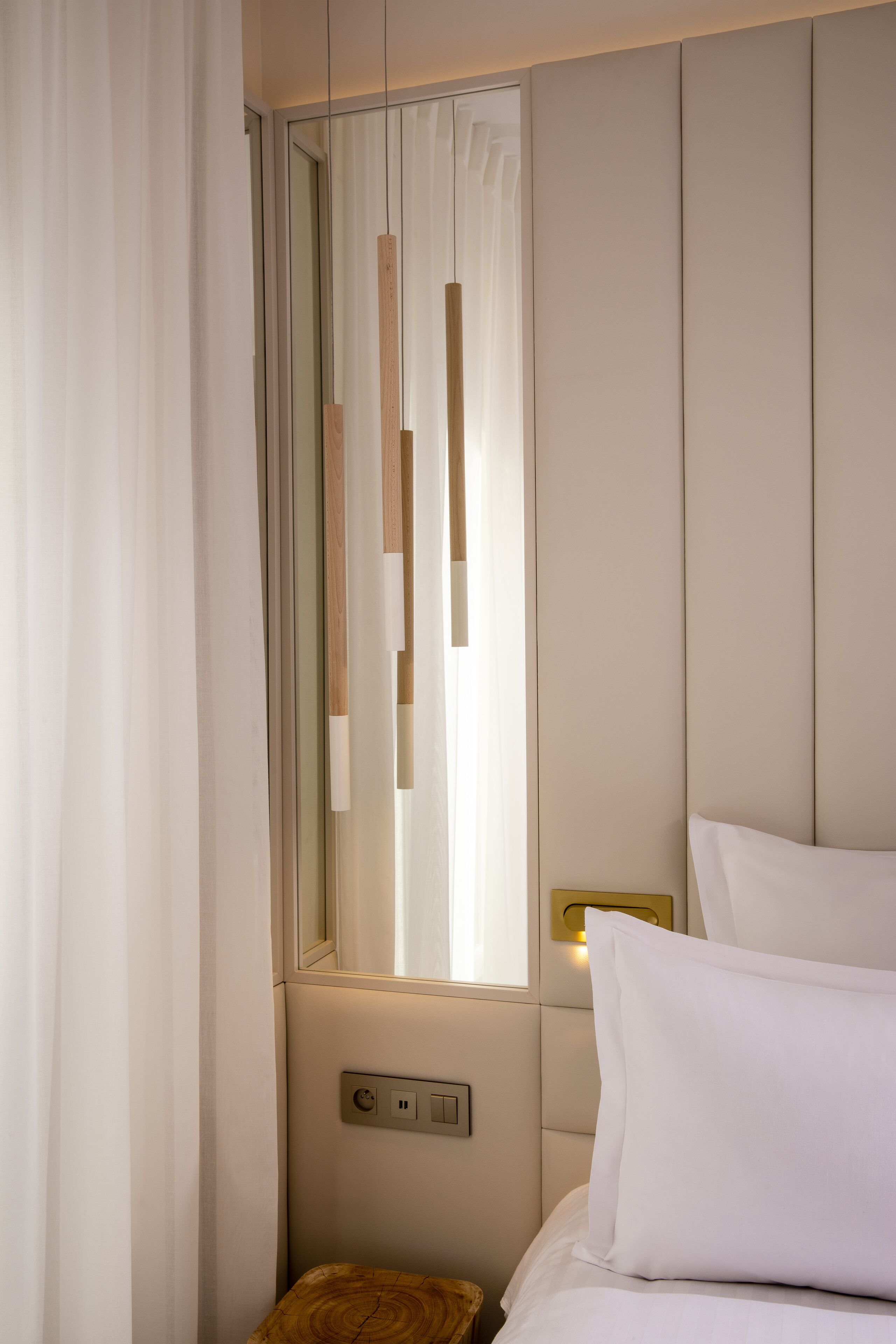 A hotel room with a bed, a nightstand, a mirror, and a window with vertical blinds.