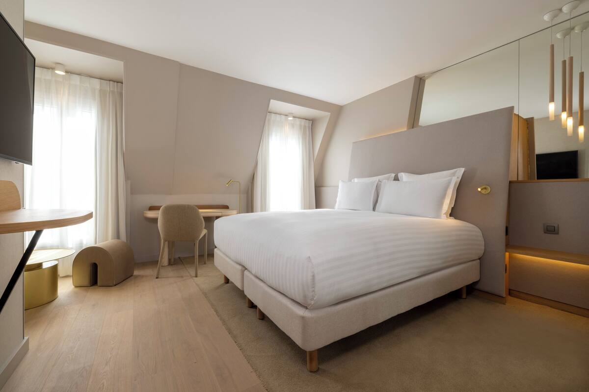 Une chambre moderne avec un grand lit, un bureau et une chaise.