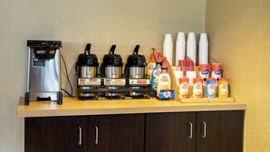 Een koffiehoek met een koffieapparaat, drie koffiehoeveelheden en verschillende opties voor melk en room.
