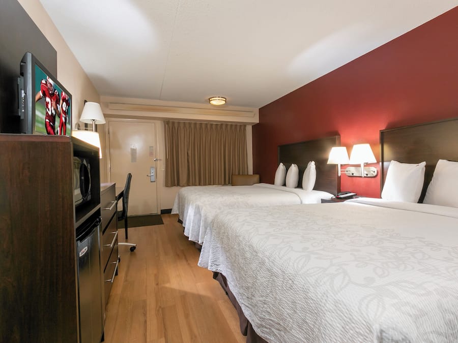 Een hotelkamer met een bed, bureau, televisie en lamp.