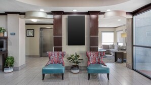 A lobby with two blue armchairs, a potted plant, a reception desk, and a large window. - Best Western Webster Hotel, Nasa (Webster)