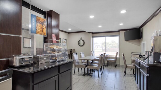 A modern kitchen with a self-service counter, a dining area with tables and chairs, and a large window providing natural light. - Best Western Webster Hotel, Nasa (Webster)