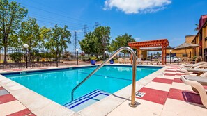 Una piscina al aire libre de temporada, sombrillas