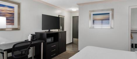 Une chambre d’hôtel comprenant un lit, un bureau avec une chaise, une télévision et une armoire.