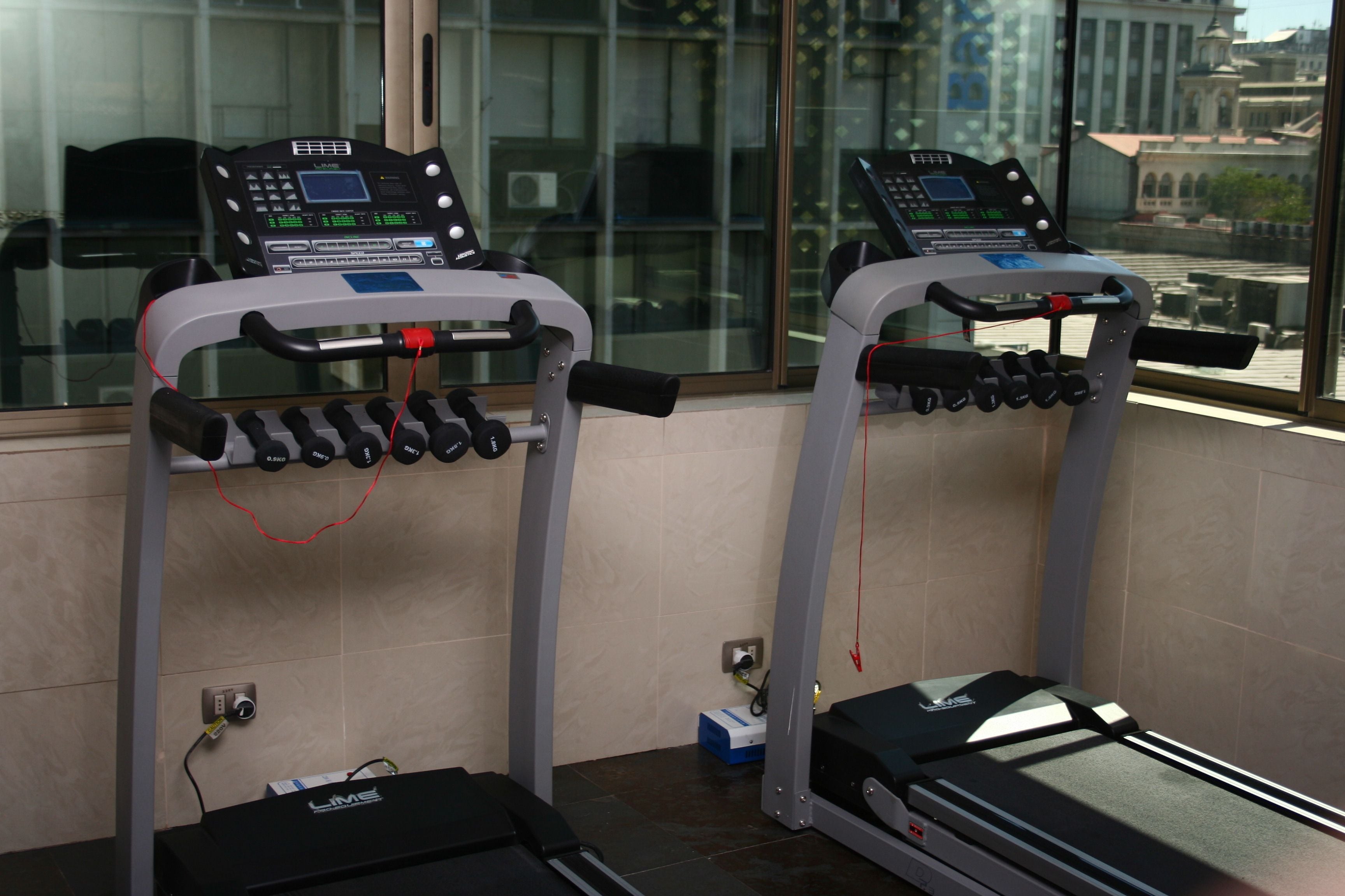 A gym with treadmills, weight machines, and a digital display.