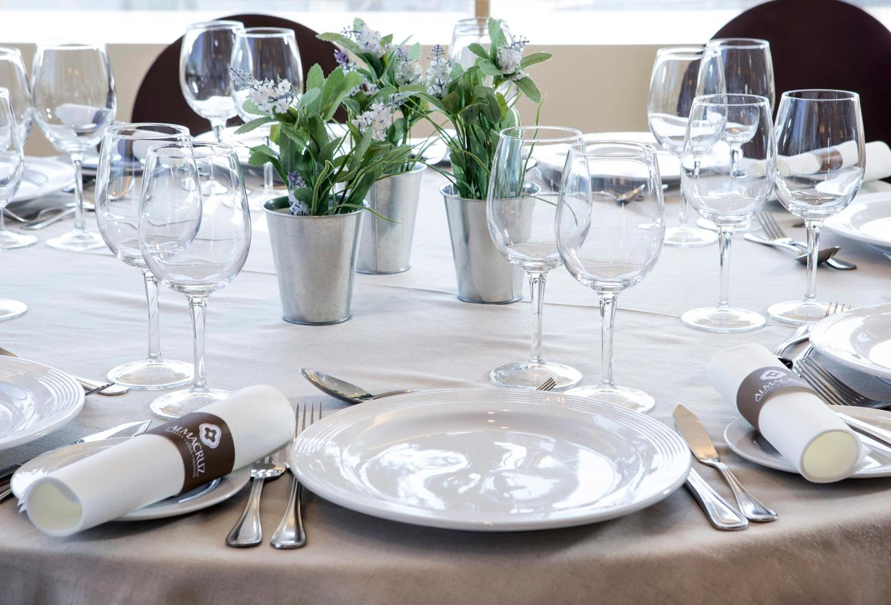 Une table dressée pour un repas formel, avec de nombreux verres à vin, des assiettes et des couverts.