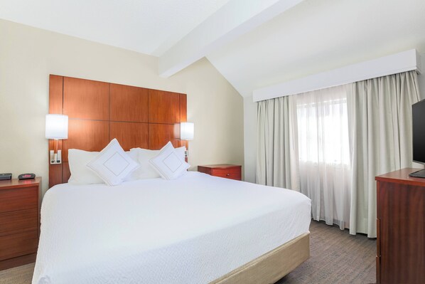 A hotel room with a large bed, wooden headboard, two bedside tables with lamps, a TV on a wooden cabinet, and a window with curtains. - Residence Inn by Marriott Atlanta Cumberland/Galleria (Smyrna)