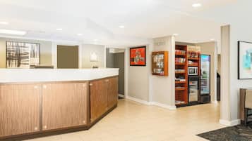 A reception area with a wooden reception desk, a refrigerator stocked with beverages, and a wall-mounted display case.