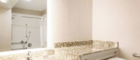 A bathroom with a marble sink, a toilet, and a shower.