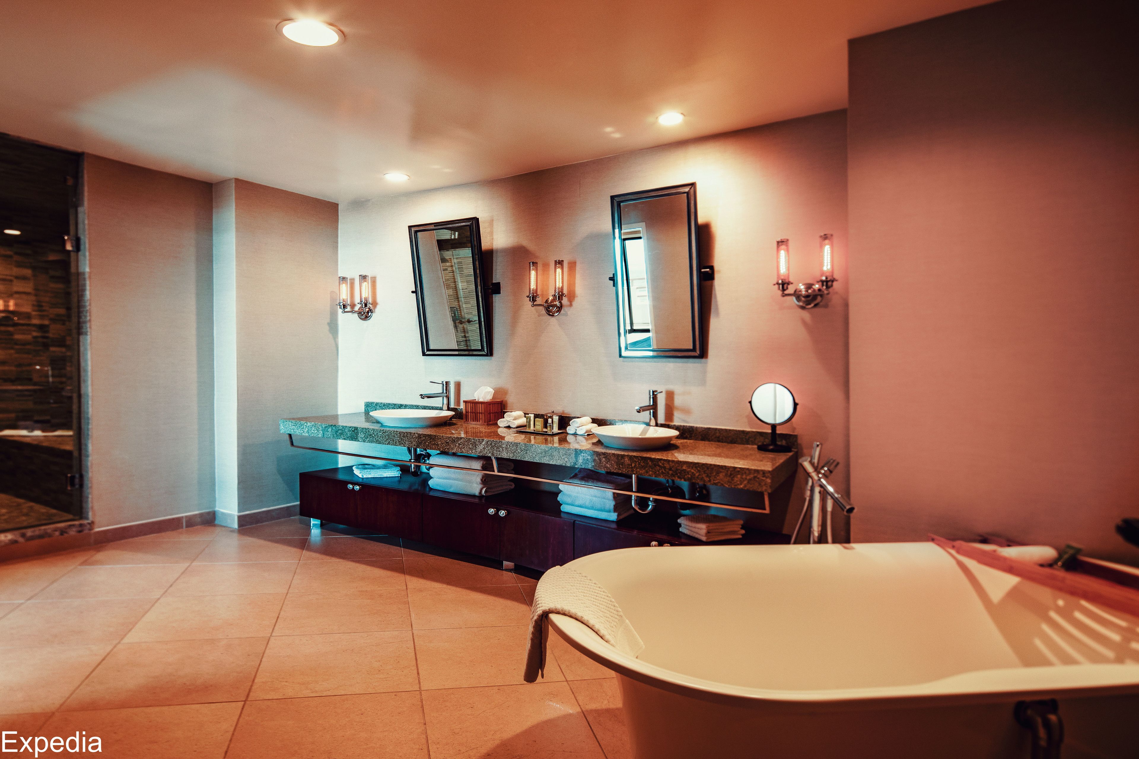 A modern bathroom with a freestanding bathtub, double sinks, and a large mirror.