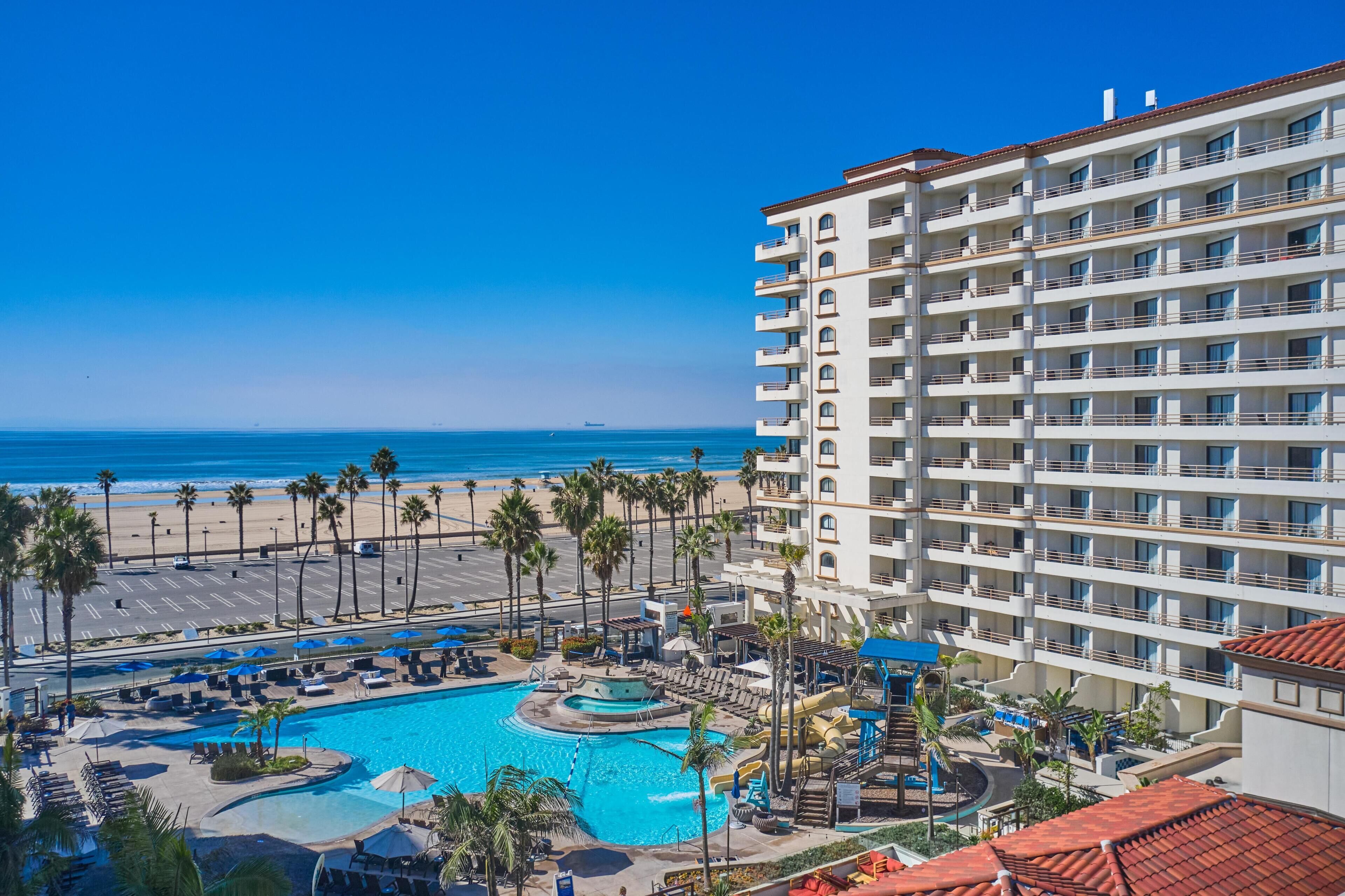 A hotel with a pool, beach view, and multiple balconies.