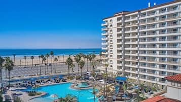 A hotel with a pool, beach view, and multiple balconies.