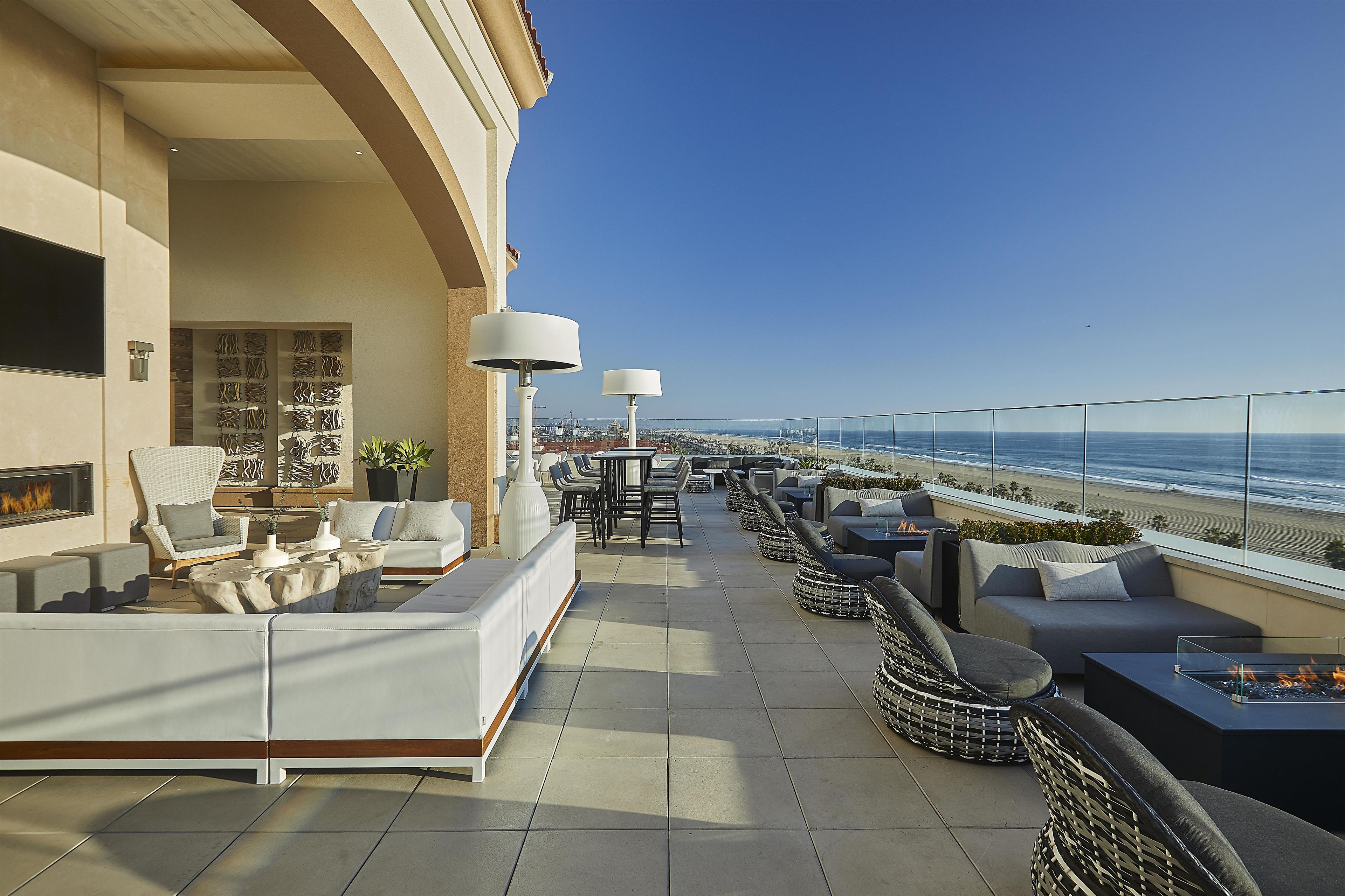 A rooftop terrace with outdoor seating, a fire pit, and a view of the beach.