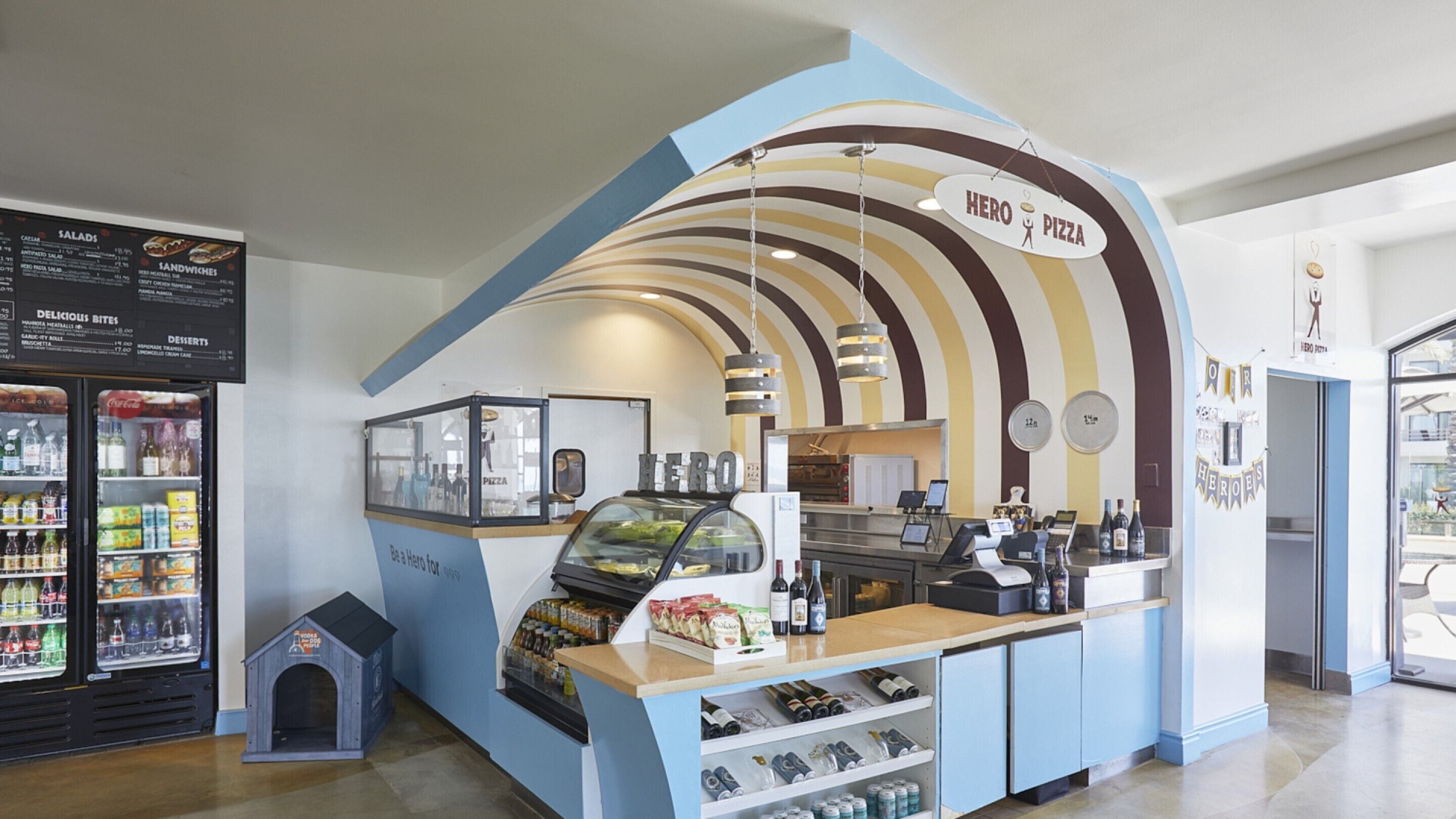 A Hero Pizza kiosk with a curved counter, a display case, and a menu board.