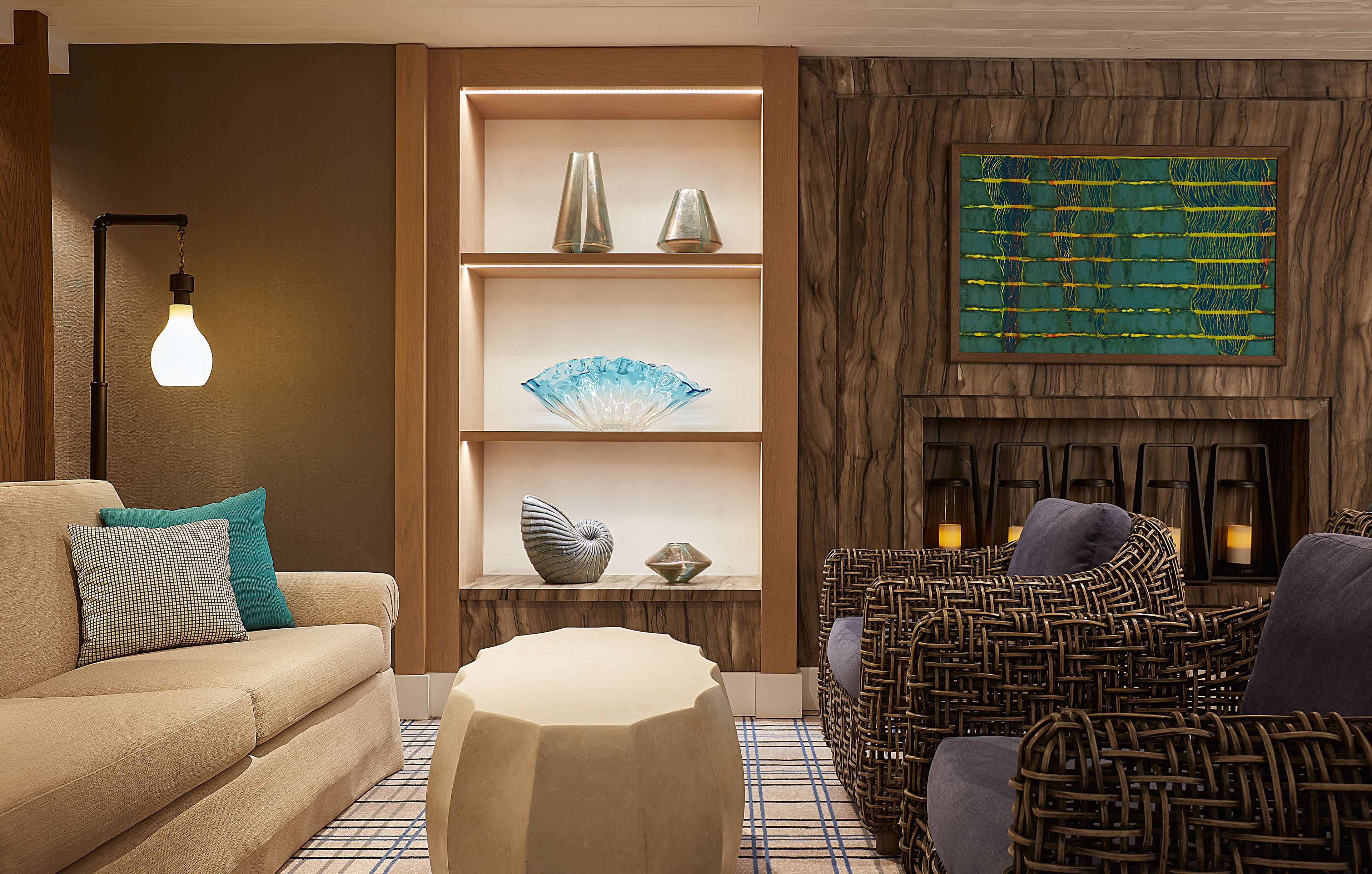 Una sala de estar moderna con sofá, una mesa de centro, sillones de mimbre, chimenea y estanterías decorativas.