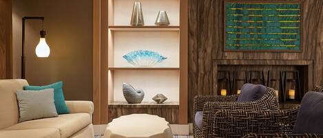 Un salon moderne comprenant un canapé, une table basse, des fauteuils en osier, une cheminée et des étagères décoratives.