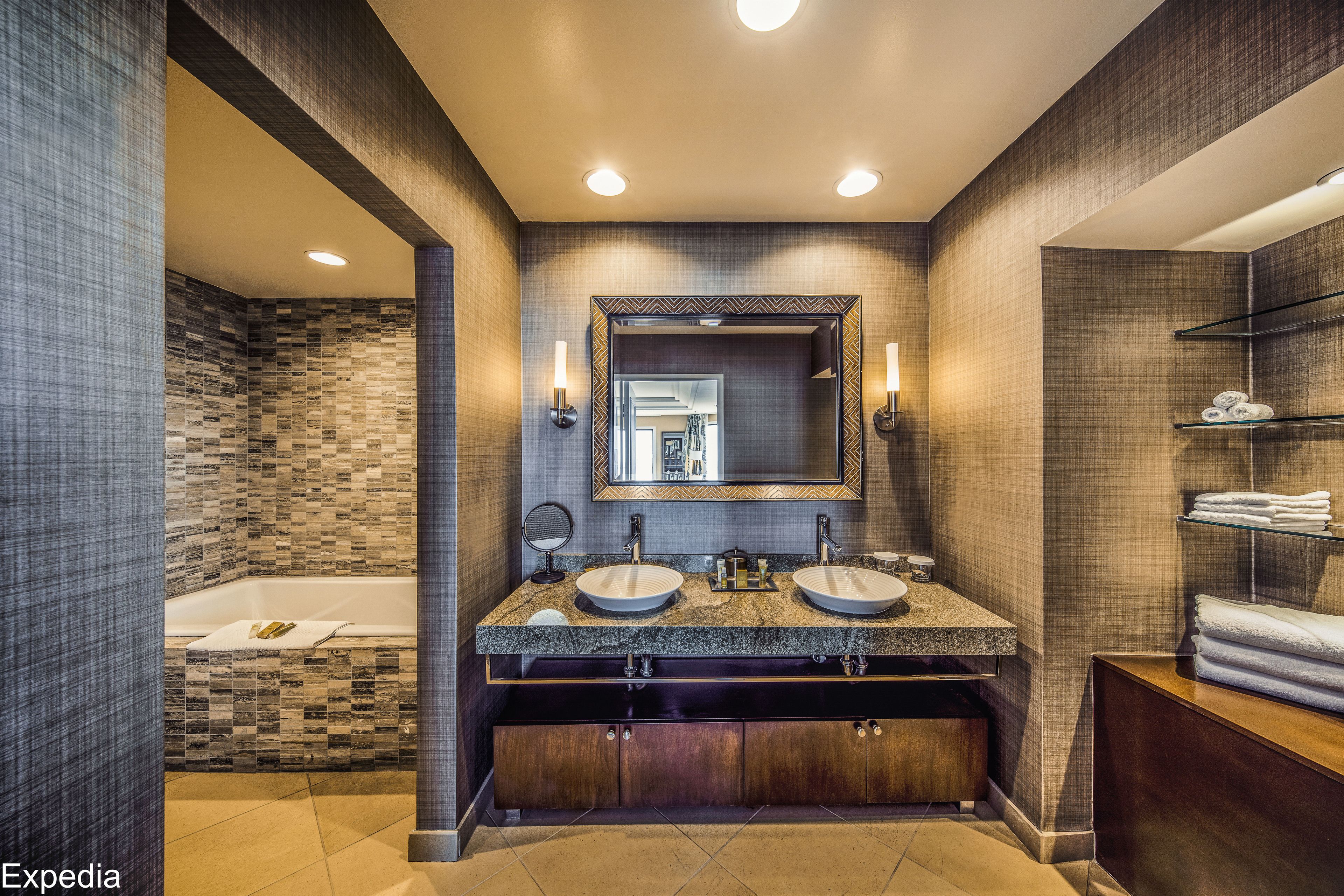 Un bagno moderno con doppio lavabo, un ampio specchio e una vasca da bagno incassata.