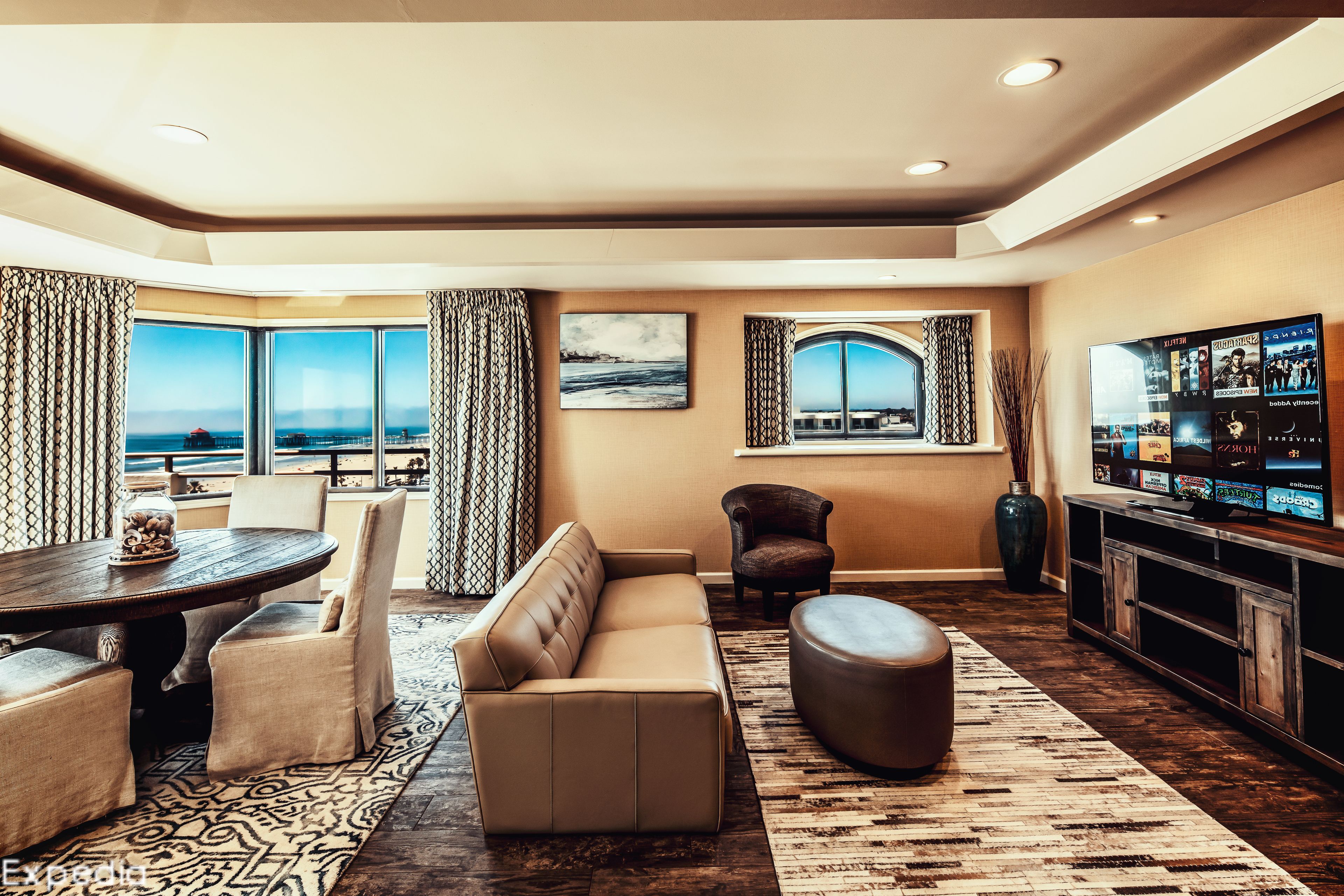 A modern living room with a large window, a sofa, a dining table, and a TV.