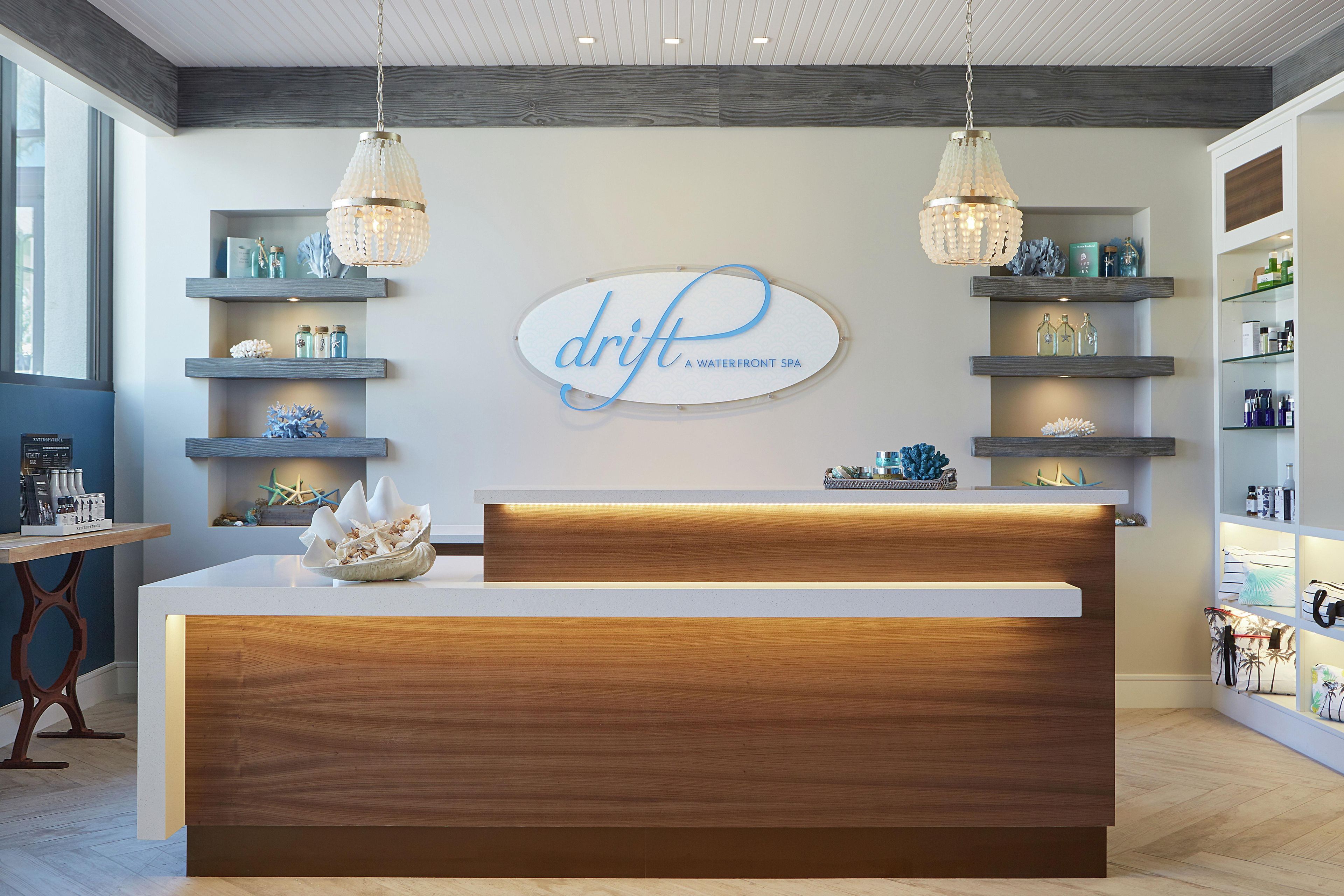 A reception desk with a wooden finish, a chandelier, and a sign that reads 'drift A waterfront spa.'