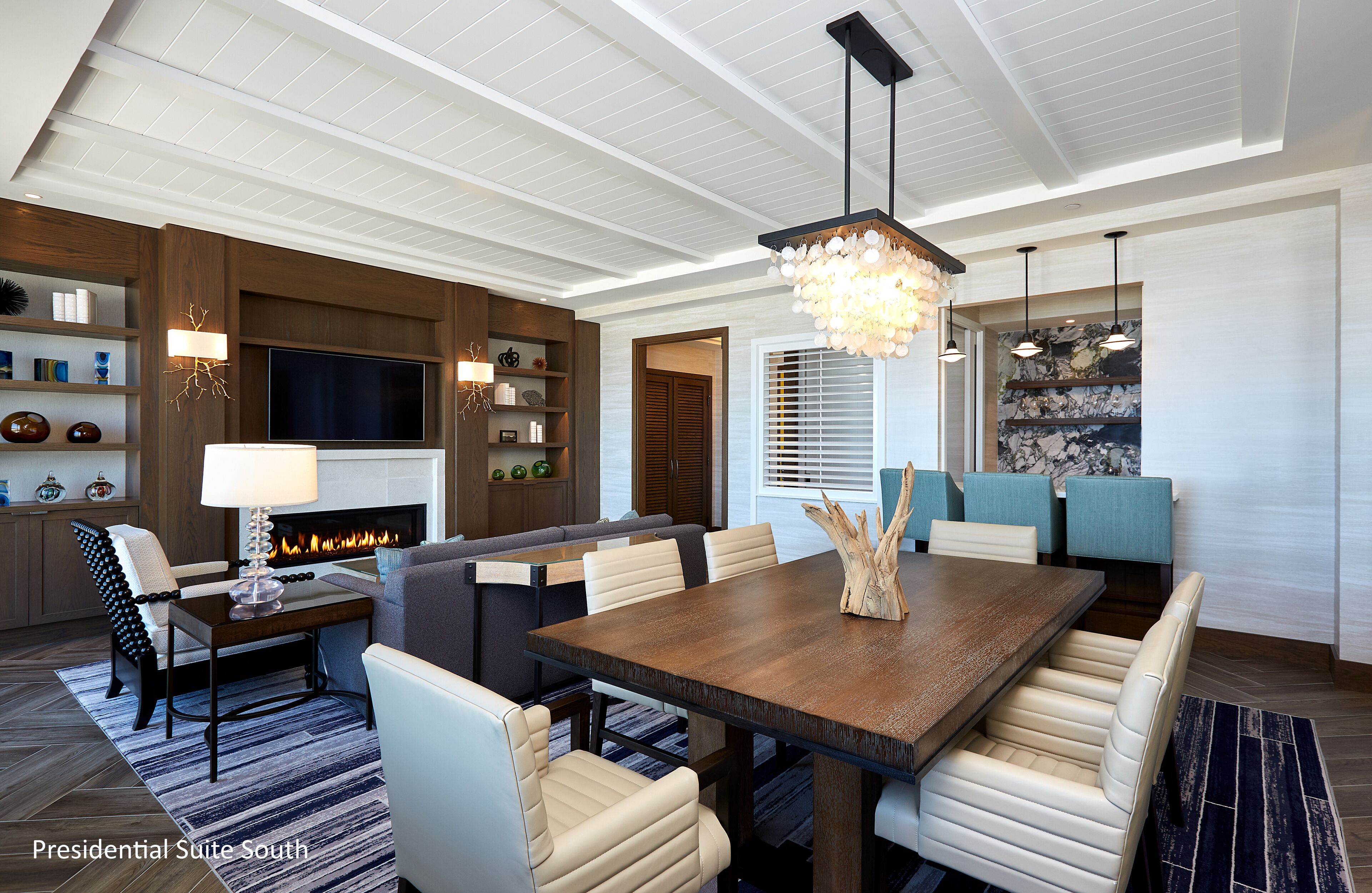 Un salón amplio con una gran mesa de comedor de madera, asientos cómodos, una chimenea y una lámpara moderna.