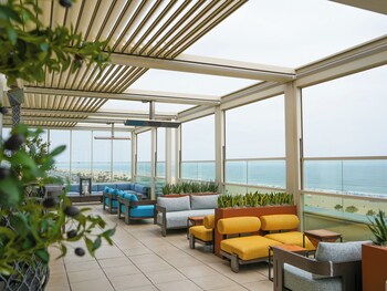 A coastal road with a beach and palm trees in the distance. at The Waterfront Beach Resort, A Hilton Hotel