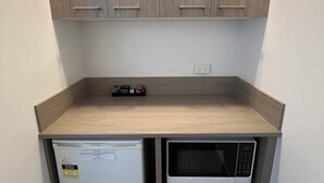 Une cuisine compacte dotée d’un réfrigérateur intégré, d’un four à micro-ondes et de meubles de rangement en bois.