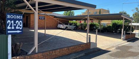A covered parking area with a sign indicating rooms 21-29.