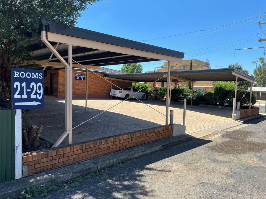 A covered parking area with a sign indicating rooms 21-29.