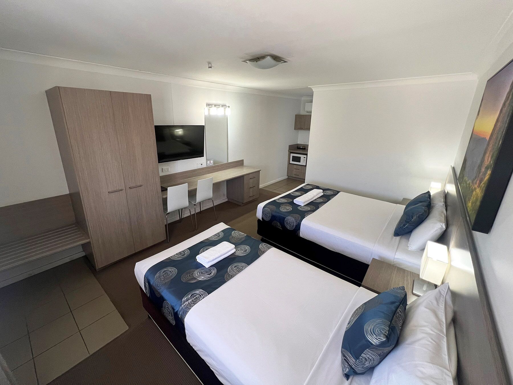 A hotel room with two beds, a TV, a desk, and a wardrobe.