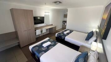 Een hotelkamer met twee bedden, een televisie, een bureau en een kledingkast.